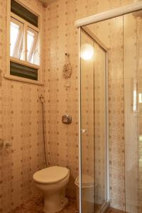 a bathroom with a toilet and a glass shower at Apartamento Resort Cabo Frio - Rua dos Biquinis in Cabo Frio