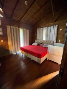 a bedroom with a large red bed in a room at Casa com piscina a 300m praia in Imbituba