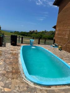 a large blue swimming pool with a water fountain at Casa com piscina a 300m praia in Imbituba