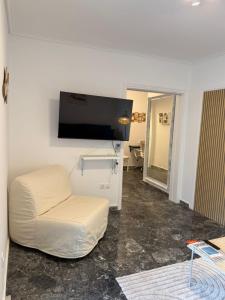 Una sala de estar con un sofá blanco y un televisor de pantalla plana. en Boho Coastal Retreat with Jacuzzi, 1 min to Beach, en Atenas