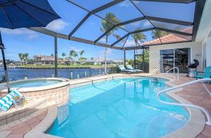 ein Swimmingpool mit Sonnenschirm in einem Haus in der Unterkunft Palm Pointe - Waterfront Vacation Rental Cape Cora in Matlacha