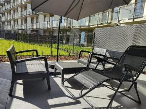 a group of chairs and an umbrella on a patio at TOTU TODAY - POSNANIA - MALTA APARTAMENTY , Faktura VAT, self check-in, bezpłatny parking in Poznań