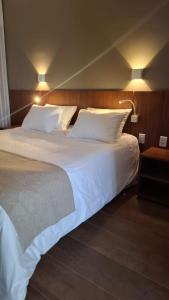 a bedroom with two beds with white sheets and lamps at Hotel C jaguariuna in Jaguariúna
