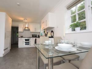 una cucina con tavolo in vetro e mobili bianchi di 2 Bed in Wroxham 56104 a Hoveton