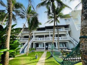 an exterior view of a resort with palm trees at Suite Lanka in Hikkaduwa
