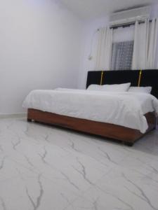 a bed in a bedroom with a marble floor at Vivi apartment hotel and suite in Sapele