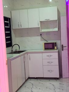 a kitchen with white cabinets and a sink and a microwave at Vivi apartment hotel and suite in Sapele