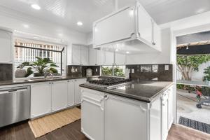 eine Küche mit weißen Schränken und einem Herd mit Backofen in der Unterkunft Iconic 4Br Bayfront Home W Unmatched Indooroutdoor Living By Beachview Rentals in Newport Beach