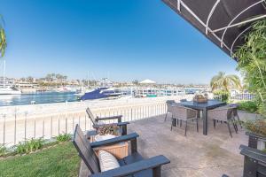 eine Terrasse mit Tischen und Stühlen sowie einen Yachthafen in der Unterkunft Iconic 4Br Bayfront Home W Unmatched Indooroutdoor Living By Beachview Rentals in Newport Beach