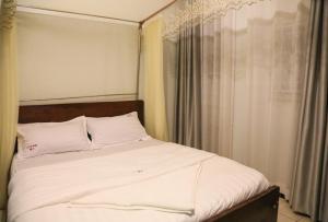 Una cama con sábanas blancas y almohadas en una habitación. en JD LUXURY HOTEL Jinja, en Nalakonge