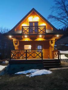 a log cabin with lights on the front of it at Domek w dolinie ciszy Pieniny in Grywałd