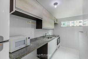 a white kitchen with a sink and a microwave at Apto 2 Quartos a 200 m da Praia MAO0203 in Cururupe