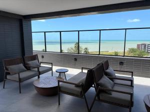a balcony with chairs and a table and a view of the ocean at 105 Dutra Ocean Flat - Take Home in Tambaú