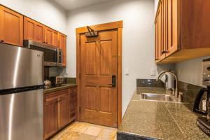 a kitchen with wooden cabinets and a stainless steel refrigerator at Hyatt Main Street Station Studio in Breckenridge