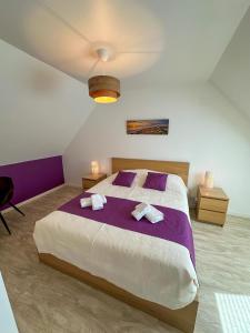 a bedroom with a large bed with two towels at KER EOZEN - Maison confortable en plein centre in Plouguerneau