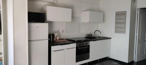 a kitchen with white cabinets and a black and white refrigerator at La marine in Rogliano