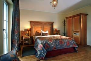 a bedroom with a large bed and a chandelier at Ampervilla Hotel in Fahrenzhausen