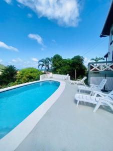 a swimming pool with white lounge chairs and a house at Paradise View in Gros Islet