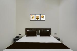 une chambre avec un grand lit blanc avec des oreillers noirs dans l'établissement Hotel O Choudhary Hotel and Resort, à Anūpnagar