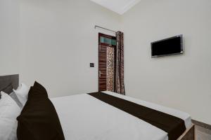 une chambre avec un lit avec une télévision au mur dans l'établissement Hotel O Choudhary Hotel and Resort, à Anūpnagar 21 autres photos