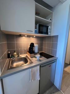 a kitchen with a sink and a microwave at Appart'Hotel - Gare TGV - Courtine - Confluence - 407 in Avignon +16 photos