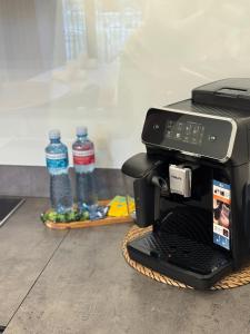 a black coffee maker sitting on a basket with water bottles at La Tereza Apartments in Ķesterciems