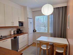 Una cocina con gabinetes blancos y una mesa y sillas. en Ihana kaksio lähellä luontoa!, en Tampere