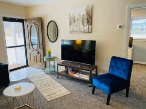 un soggiorno con TV e sedia blu di Lake Trail Cottage a Michigan City