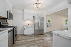 una cucina con mobili bianchi e un frigorifero in acciaio inossidabile di Lake Trail Cottage a Michigan City Altre 16 foto