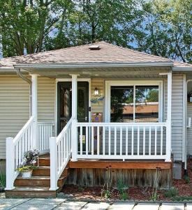una piccola casa con portico e recinzione bianca di Lake Trail Cottage a Michigan City