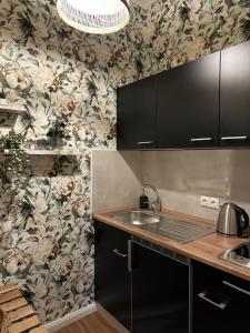 Una cocina con armarios negros y papel pintado floral en Attraktives City-Apartment No4, en Bremen