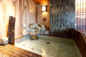 a hot tub in a room with rocks in it at Dormy Inn Nagano in Nagano