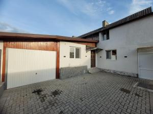 a garage with two white garage doors and a building at Casa Lumi in Petrila