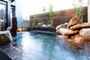a hot tub in a backyard with rocks at Dormy Inn Nagano in Nagano