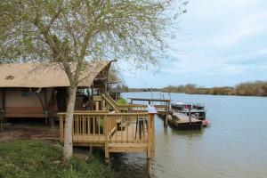 a house on the water with a dock and a boat at Cozy Glamping Minutes from SpaceX Launches in Colonia Acres +15 photos