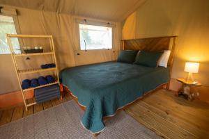 a bedroom with a bed with a green comforter and a window at Settle Into a Cozy Lakeside Glamping Escape in Onalaska