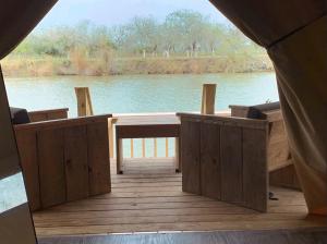 a wooden deck with a view of a lake at Boutique Safari Tent Near SpaceX Launch Site in Colonia Acres