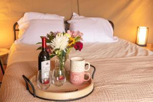 een dienblad met een fles wijn en bloemen op een bed bij Cozy Wine Country Retreat at Painted Prairie in Currie