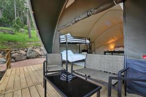 a tent with a bed and a chair on a deck at Glamping in Nature Near Mt Rushmore in Keystone