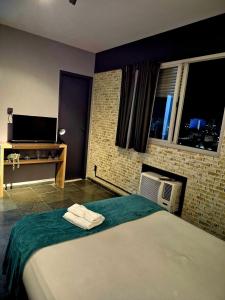 une chambre avec un grand lit et une télévision dans l'établissement studio estilo industrial Centro, à Campos dos Goytacazes