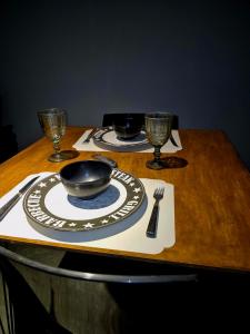 une table en bois avec deux assiettes et des verres dans l'établissement studio estilo industrial Centro, à Campos dos Goytacazes