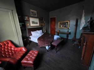 een slaapkamer met een bed, een bank en een stoel bij The Lincoln House Inn in Bowling Green