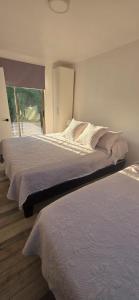 a bedroom with two beds and a large window at Casa mediterránea Villamar Guanaqueros in Guanaqueros