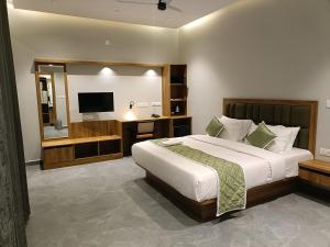 een slaapkamer met een groot bed en een televisie bij Veera Resort in Attigundi