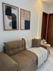 un divano marrone in soggiorno con due immagini di REFUGIO DO CRUZEIRO - GRAVATa a Gravatá