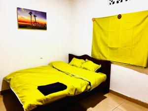 a bedroom with a yellow comforter on a bed at Kalpho Art Center in Kigali