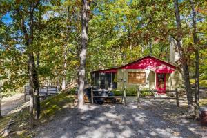 a small cabin in the woods with trees at Cottage Inn The Woods -- Pond, Pet Friendly, Grill, Wifi, Fire Pit, Deck, Screen Porch, Fireplace, Private in Berkeley Springs