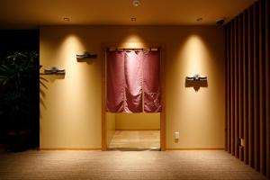 a room with a red curtain and a window at Dormy Inn Nagano in Nagano