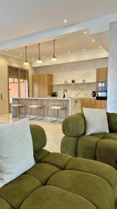 a living room with two green couches and a kitchen at Exceptional Marrakech Villa 5 Bedrooms & Pool in Oulad Akkou