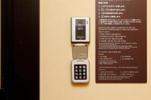 an electronic device on a wall next to a menu at Dormy Inn Nagano in Nagano